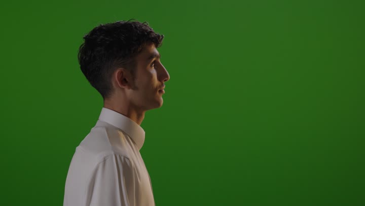 طالب عربي أمام خلفية خضراء يبتسم للكاميرا