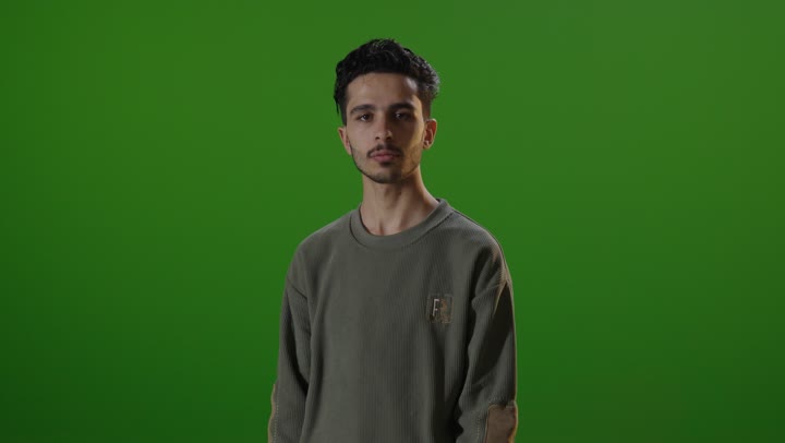 طالب مدرسة شاب أمام خلفية كروما خضراء في استوديو