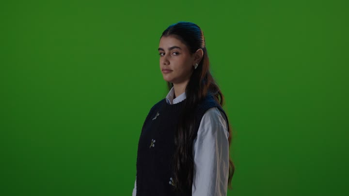 طالبة تبتسم أمام خلفية خضراء في الاستوديو