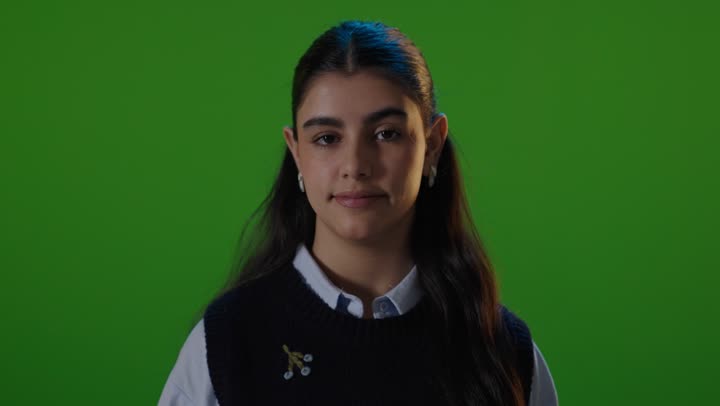 طالبة مدرسة تعطي إشارة الإعجاب خلفية خضراء