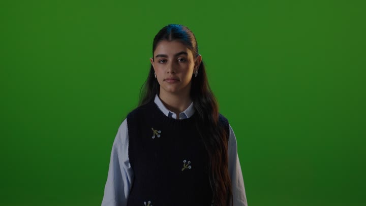 طالبة مدرسة ترفع يدها للتوقف خلفية خضراء