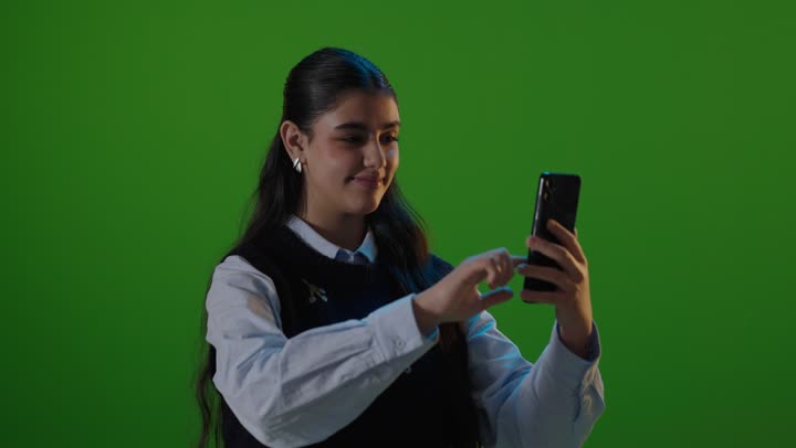 طالبة تستخدم الهاتف المحمول أمام خلفية خضراء