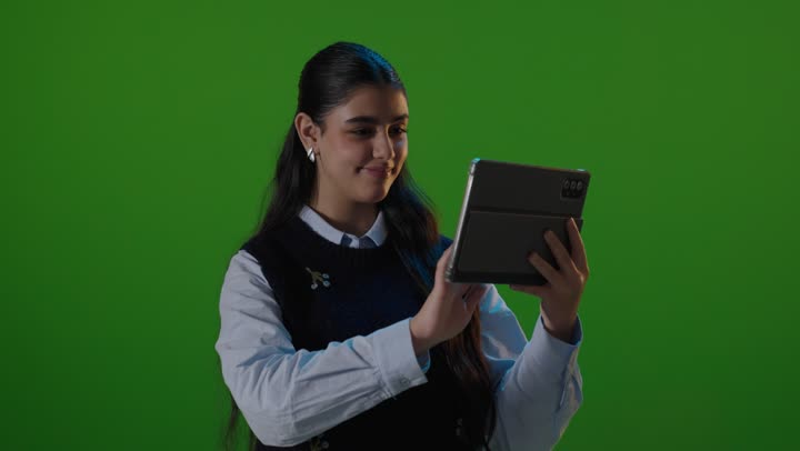 طالبة تستخدم جهاز لوحي أمام خلفية خضراء كروما