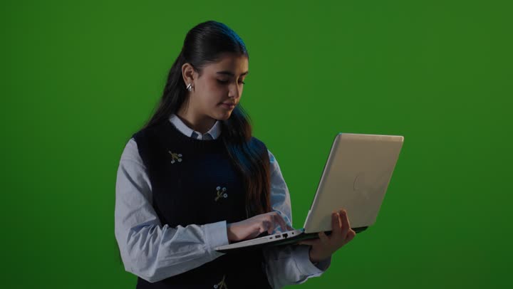امرأة سعودية تستخدم الكمبيوتر المحمول أمام خلفية خضراء