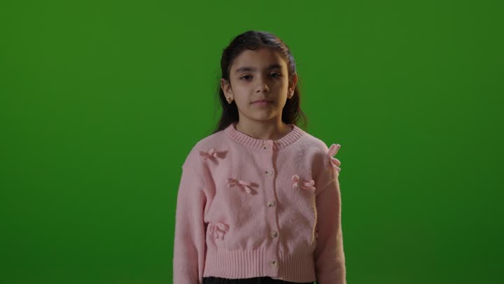 طفلة تشير بالإبهام للأعلى أمام خلفية خضراء