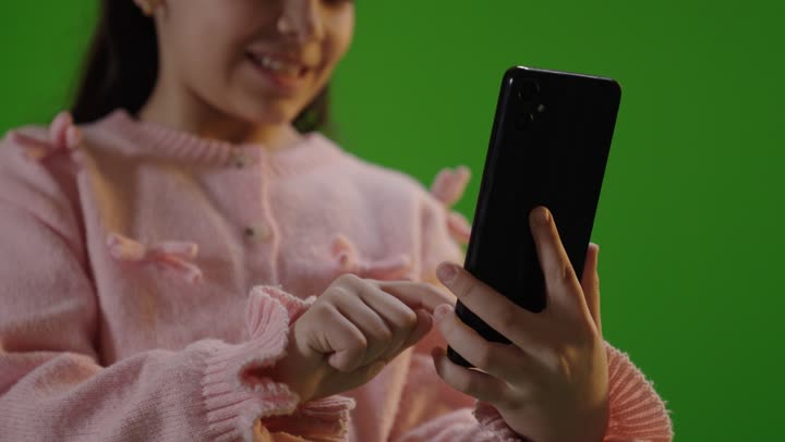 طفلة عربية تستخدم هاتف ذكي أمام خلفية خضراء كروما