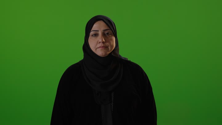 امرأة عربية بالحجاب أمام شاشة خضراء تبتسم