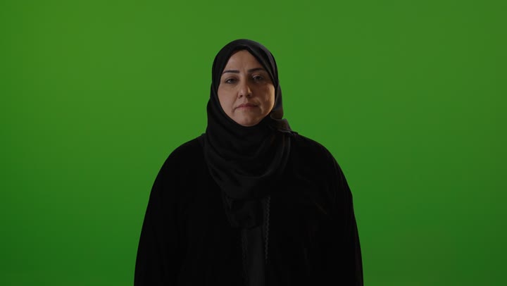 امرأة عربية بالحجاب أمام الكروما الخضراء ترفع الإبهام
