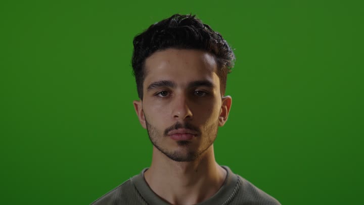 شاب عربي يقوم بإشارة التوقف خلفية خضراء كروما استوديو