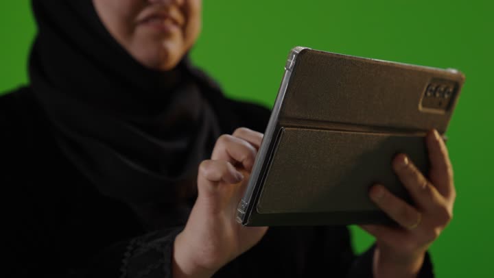 امرأة عربية تستخدم جهازاً لوحياً رقمياً خلفية خضراء كروما