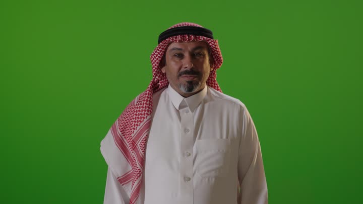 رجل سعودي يتحدث أمام كروما خضراء في استوديو احترافي