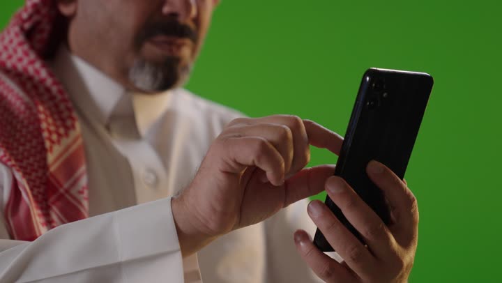 رجل سعودي يستخدم الهاتف الذكي بخلفية كروما خضراء