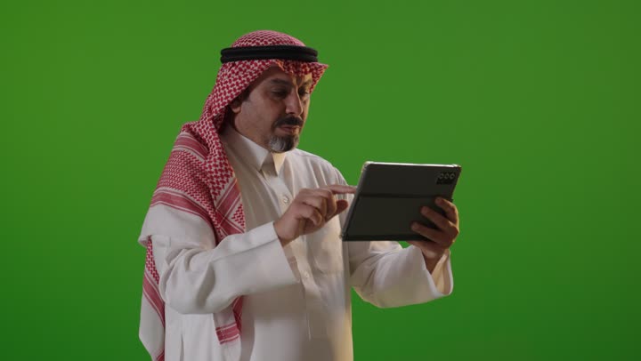رجل سعودي يستخدم جهاز لوحي بخلفية كروما خضراء