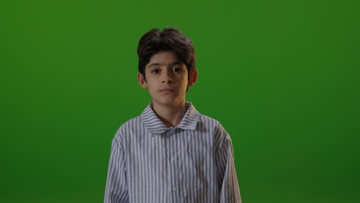 طفل عربي يبتسم أمام خلفية خضراء في الاستوديو