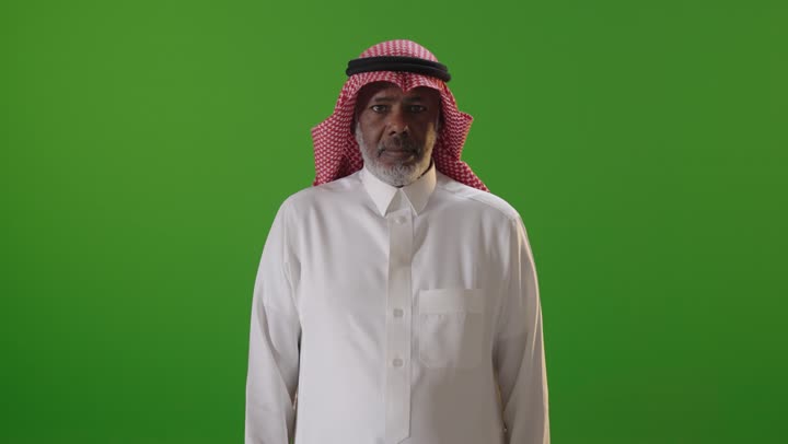 رجل سعودي يشير بالإعجاب أمام خلفية خضراء