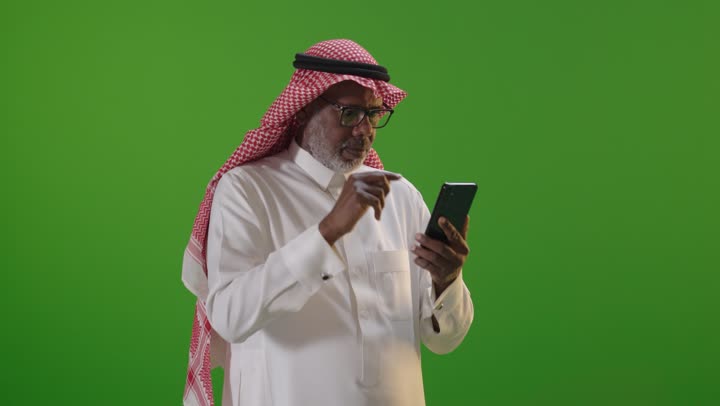Senior Saudi Man Using Smartphone on Green Screen