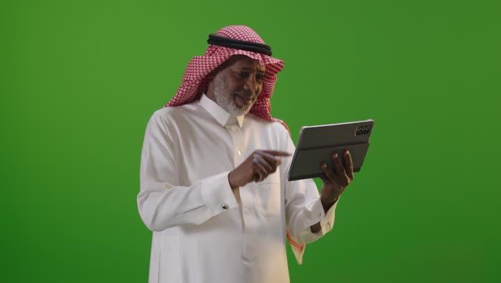 Saudi Man in Traditional Dress Using Tablet on Green Screen