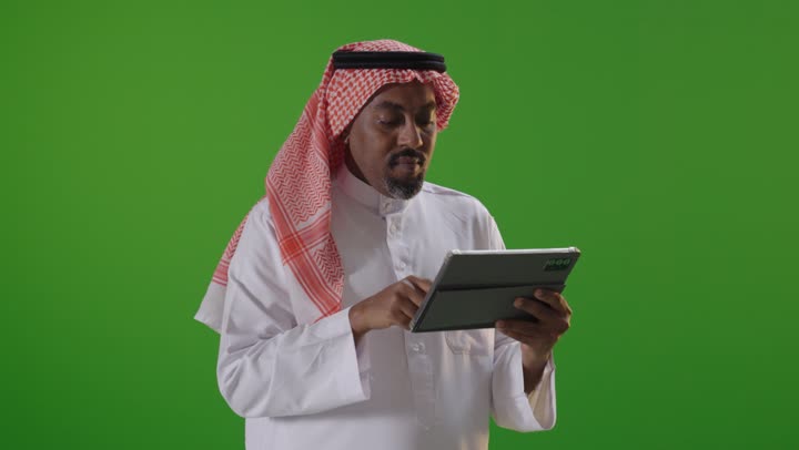 رجل عربي يستخدم جهاز لوحي أمام خلفية كروما
