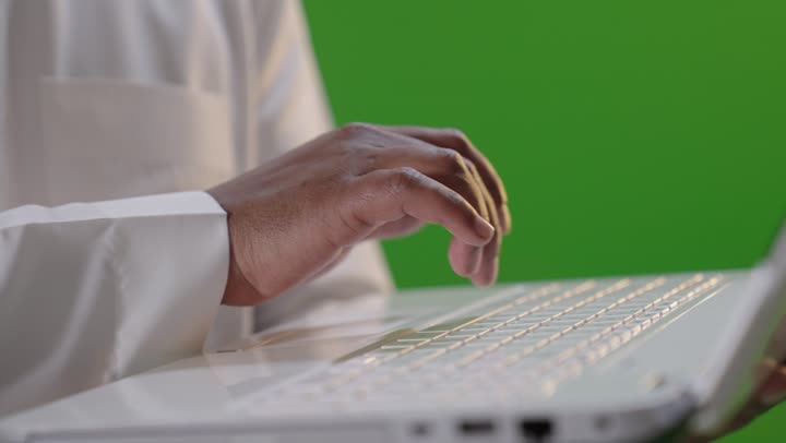 رجل سعودي يكتب على لابتوب شاشة خضراء
