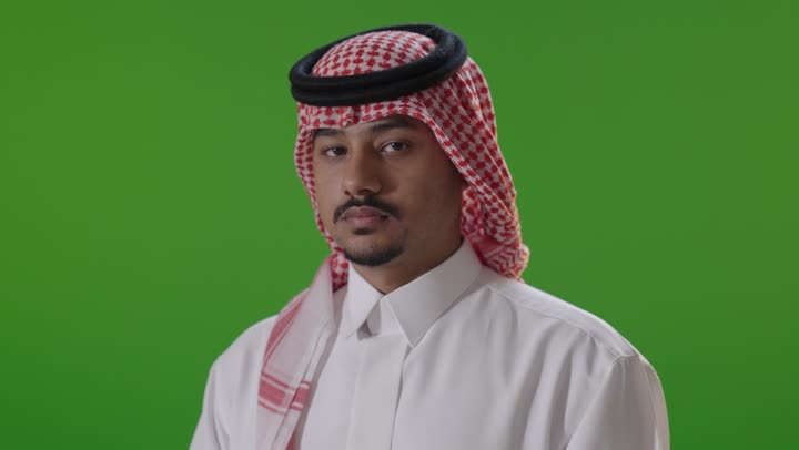 رجل سعودي أمام خلفية خضراء يبتسم للكاميرا