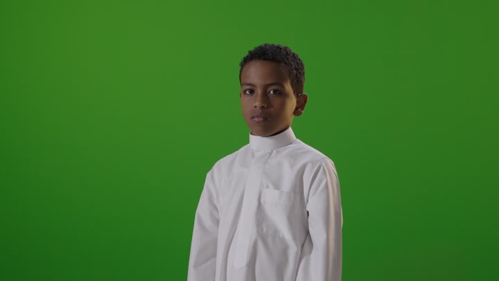 طفل سعودي بالثوب التقليدي أمام خلفية خضراء