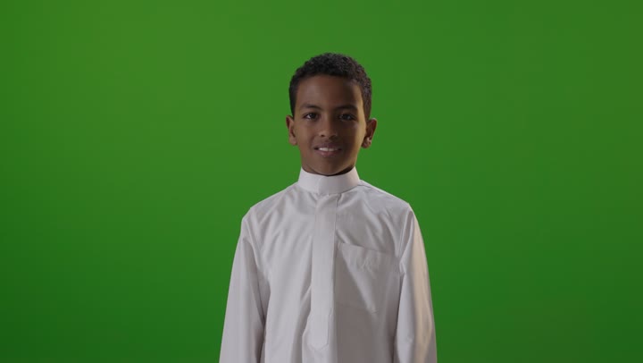 طفل سعودي بالثوب يرفع إبهامه خلفية خضراء