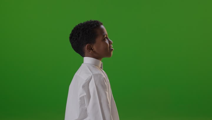 طفل سعودي بالثوب الأبيض يبتسم أمام خلفية خضراء