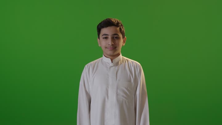 فتى سعودي بالثوب يرفع الإبهام خلفية خضراء