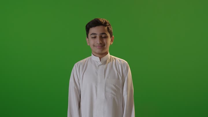 طفل سعودي بالثوب يشير بالإعجاب خلفية خضراء