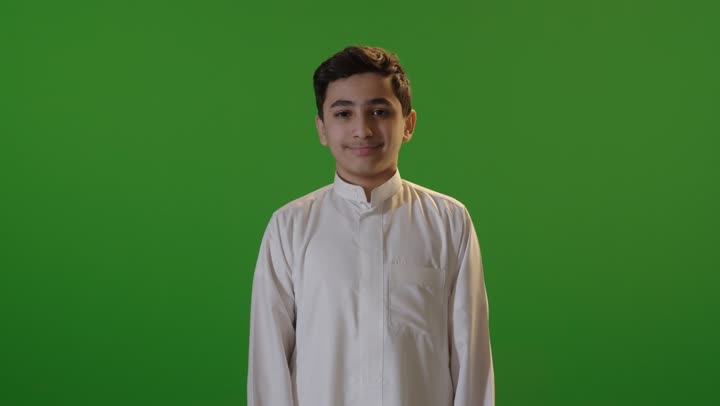 ولد سعودي بالثوب يرفع إبهامه أمام خلفية خضراء