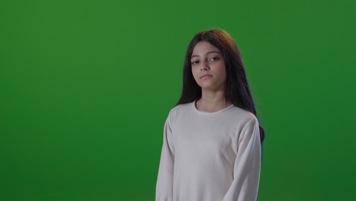 طفلة سعودية تكتف ذراعيها أمام شاشة خضراء