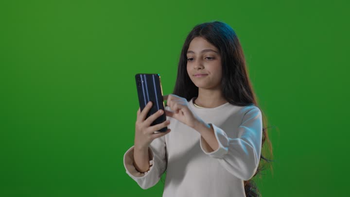 طفلة سعودية تستخدم الهاتف الذكي أمام شاشة خضراء