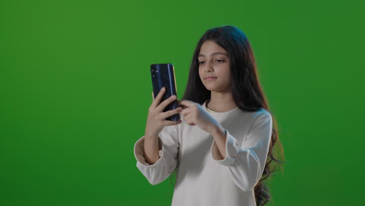 فتاة سعودية تستخدم الهاتف الذكي أمام خلفية خضراء