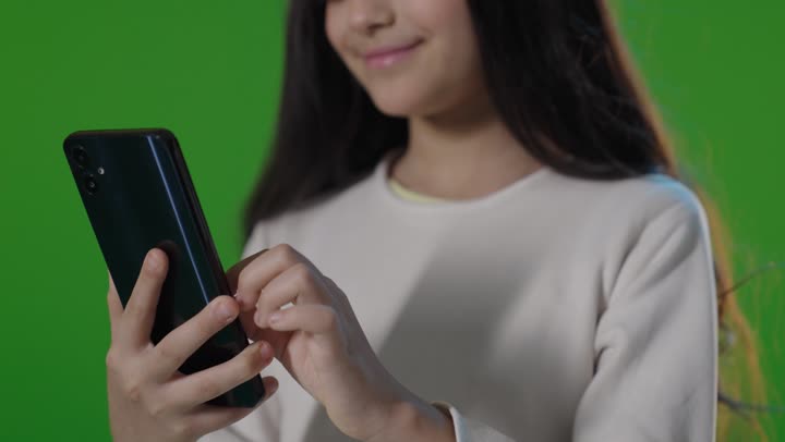 فتاة سعودية تتفاعل مع الهاتف الذكي أمام الكروما الخضراء