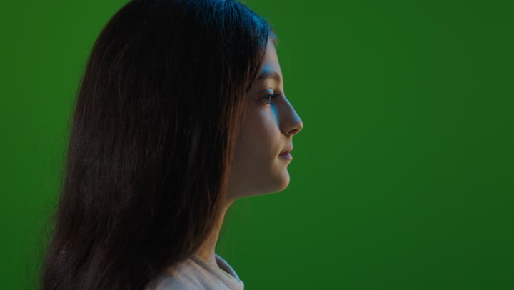 فتاة سعودية شابة تبتسم أمام خلفية خضراء كروما