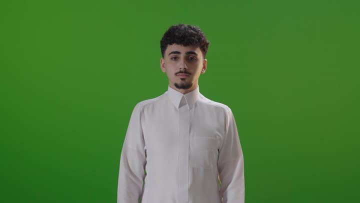 شاب سعودي يقوم بإيماءة الإبهام للأسفل أمام خلفية خضراء