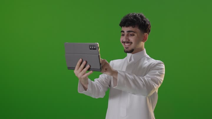 Smiling Saudi Man Using Digital Tablet on Green Screen