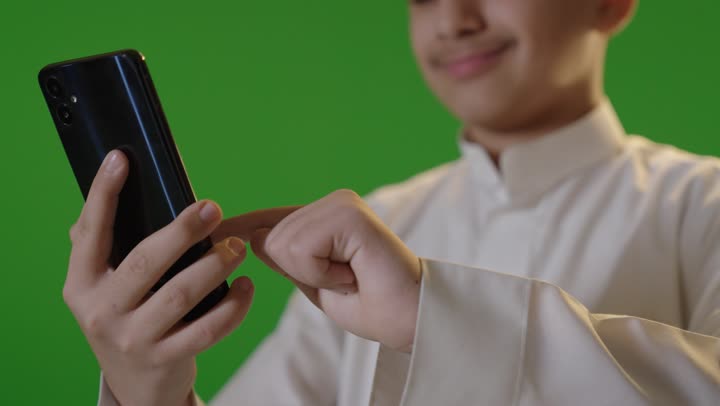 ولد سعودي يستخدم هاتف ذكي على خلفية خضراء