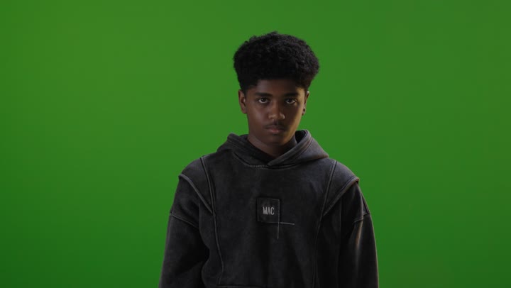 شاب سعودي يشير بالإبهام لأسفل خلفية خضراء