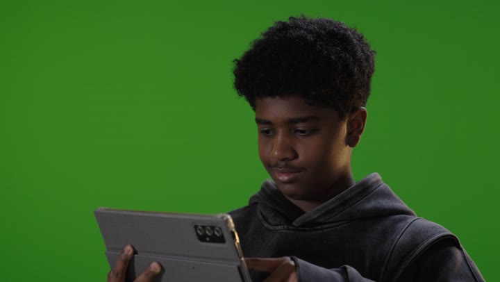 فتى سعودي يستخدم تابلت أمام كروما خضراء