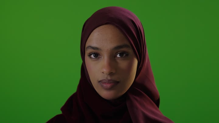 امرأة سعودية تشير بالتوقف أمام خلفية شاشة خضراء