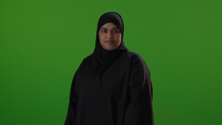 امرأة سعودية بالعباءة السوداء على خلفية كروما خضراء
