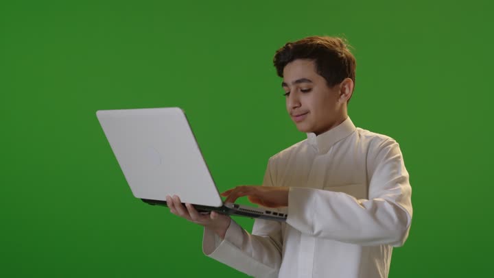 فتى سعودي يستخدم كمبيوتر محمول على خلفية كروما خضراء