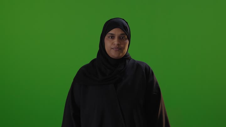 امرأة سعودية بالعباءة إشارة الإبهام خلفية خضراء