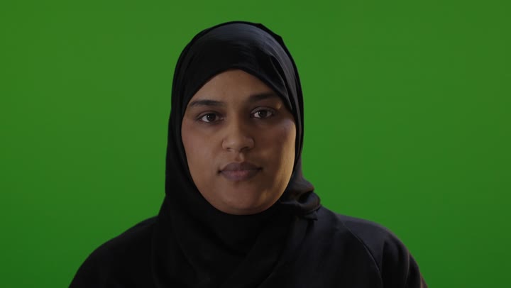 امرأة سعودية أمام شاشة خضراء تقوم بإيماءة الرفض