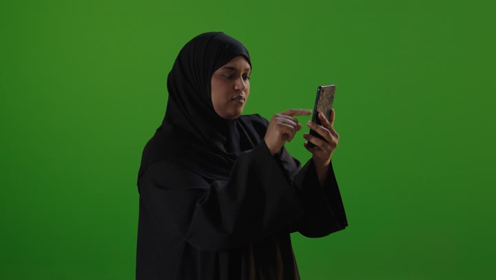 امرأة سعودية تستخدم الهاتف الذكي أمام خلفية خضراء كروما