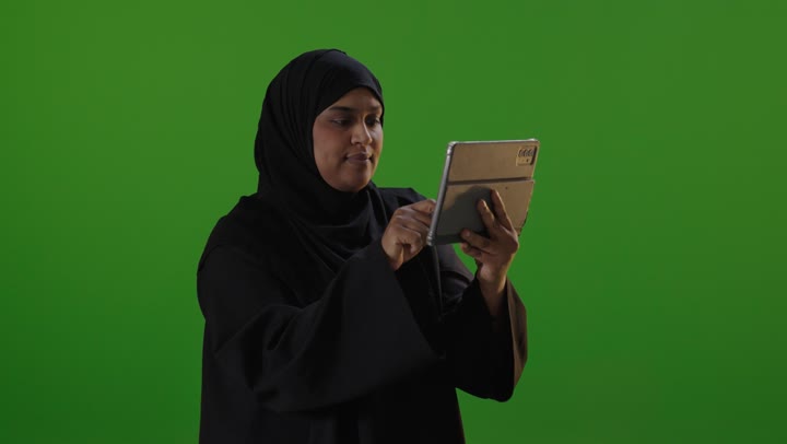 امرأة سعودية تستخدم جهاز لوحي على خلفية خضراء
