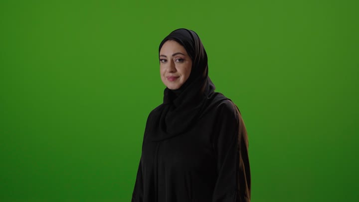 امرأة سعودية بالعباءة أمام كروما خضراء