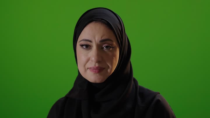 امرأة سعودية تشير بالتوقف أمام شاشة خضراء