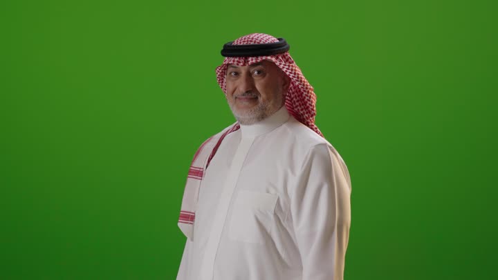 رجل سعودي بالزي التقليدي يبتسم أمام خلفية خضراء